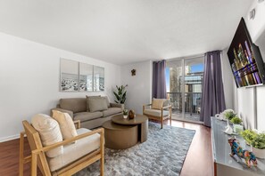 A modern living room with a sofa, armchair, and coffee table, a balcony with curtains, and a cityscape view. - Perfectly Located Miami 3BR with Stunning Views (Miami)