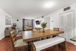 A modern living room with a wooden dining table, a sofa, and a TV. - Perfectly Located Miami 3BR with Stunning Views (Miami)