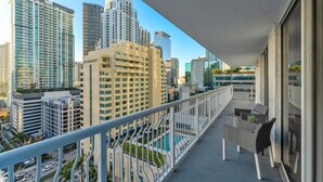 A balcony with a view of tall buildings, a pool, and a seating area. - Perfectly Located Miami 3BR with Stunning Views (Miami)