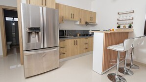 Una cocina moderna con electrodomésticos de acero inoxidable, armarios de madera y una zona de bar con taburetes.