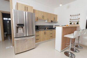 Une cuisine moderne dotée d’appareils électroménagers en acier inoxydable, de meubles de rangement en bois et d’un coin bar avec des tabourets.