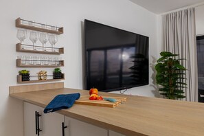 Eine moderne Küche mit einer Holzarbeitsplatte, einem an der Wand befestigten Fernseher und einer Pflanze rechts.