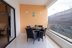 Ein Balkon mit Tisch und Stühlen, einer Topfpflanze und dekorativen Wandgestaltungen.