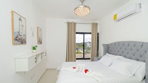 Habitació d'hotel amb un llit gran, una làmpada al sostre, una finestra amb cortines i un aire condicionat fixat a la paret.