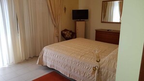 Quarto com cama, televisão, penteadeira e espelho.