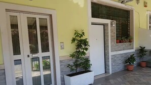 Um edifício com fachada branca, portas de vidro e plantas em vasos.