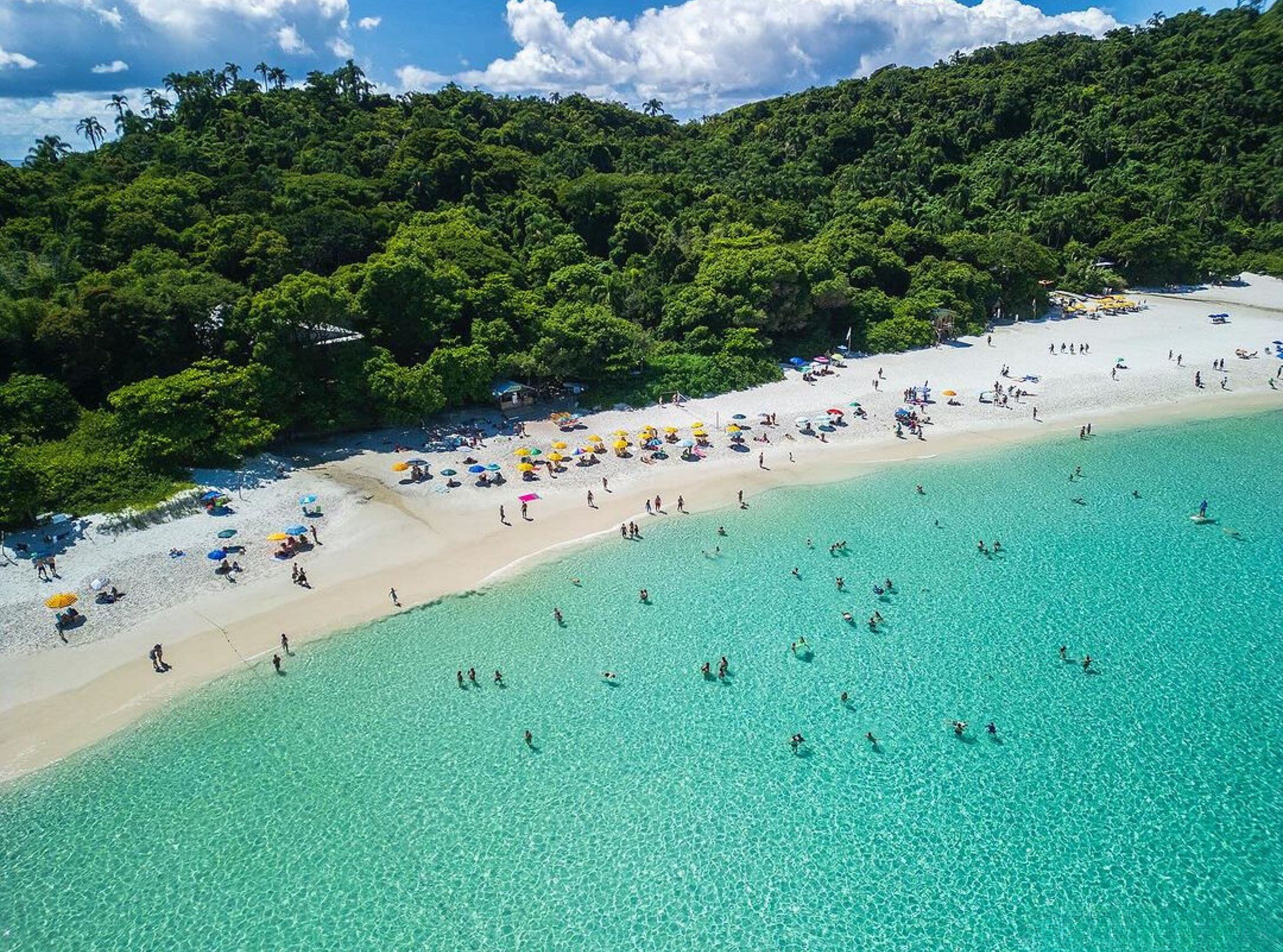 A beach with clear turquoise waters and a sandy shore.