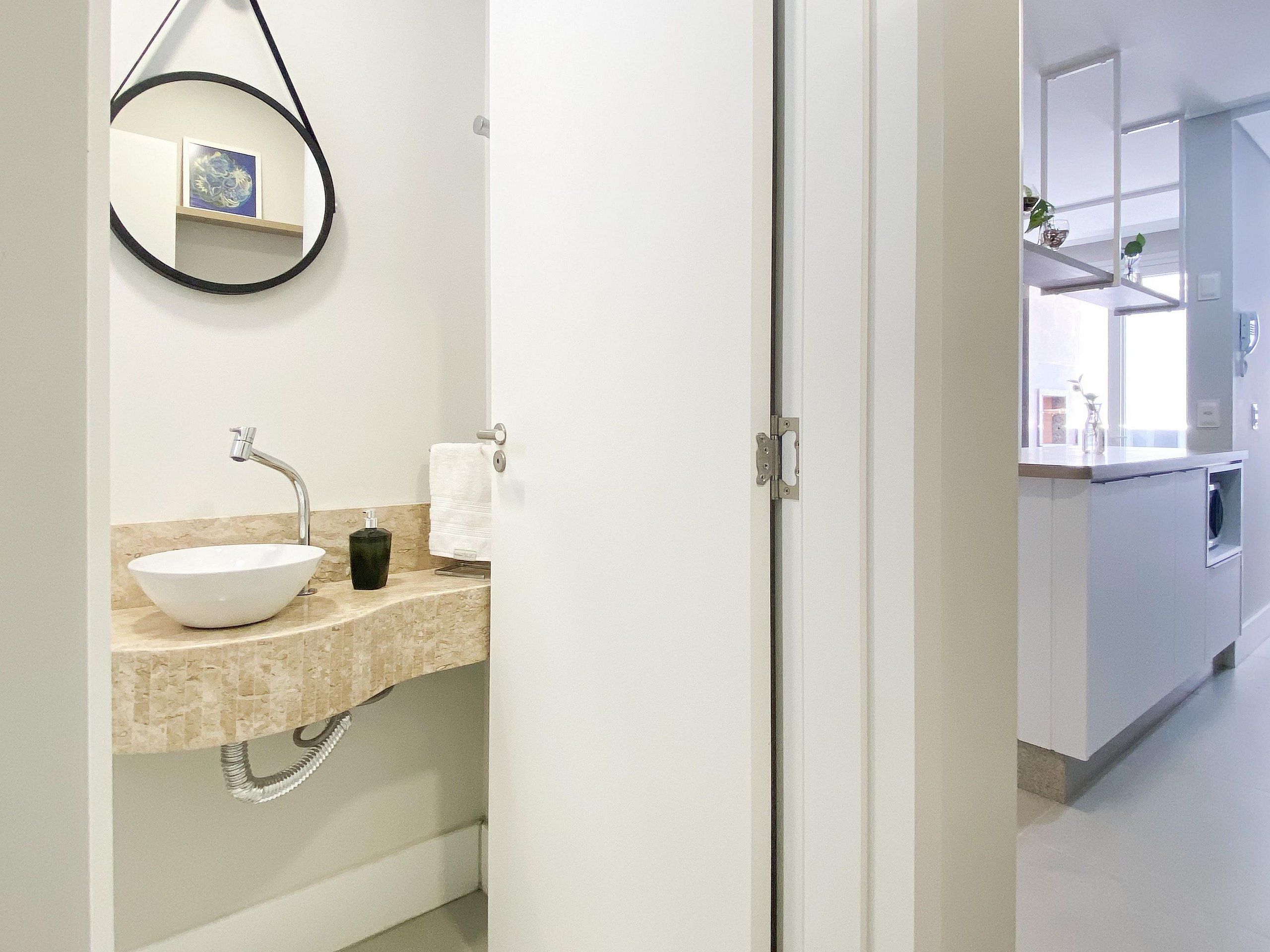 Ein modernes Badezimmer mit einem weißen Waschbecken, einem schwarzen Seifenspender und einem Handtuch an einem Handtuchhalter.