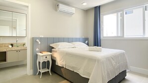 Une chambre d’hôtel moderne, équipée d’un lit, d’une table de chevet et d’une grande fenêtre avec des rideaux.