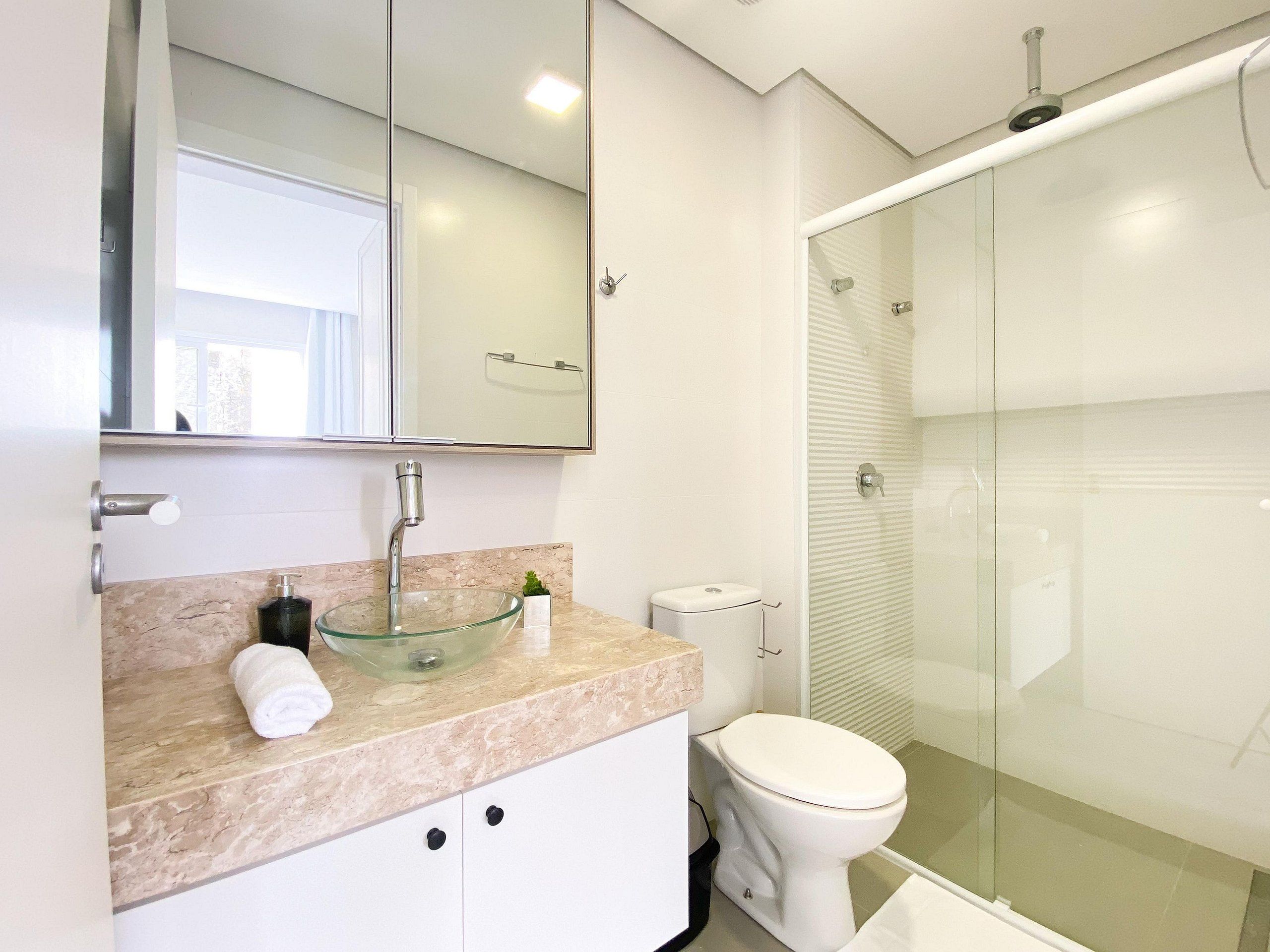 A modern bathroom with a glass bowl sink, a toilet, and a glass-enclosed shower.