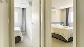 Ett hotellrum med en säng, ett nattduksbord, ett fönster med gardiner och en luftkonditioneringsanläggning på väggen.