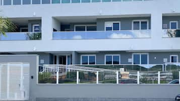A multi-story building with balconies, a gated entrance, and a clear view of the surrounding area.