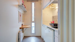 Une cuisine étroite avec une fenêtre, un radiateur et une petite table.