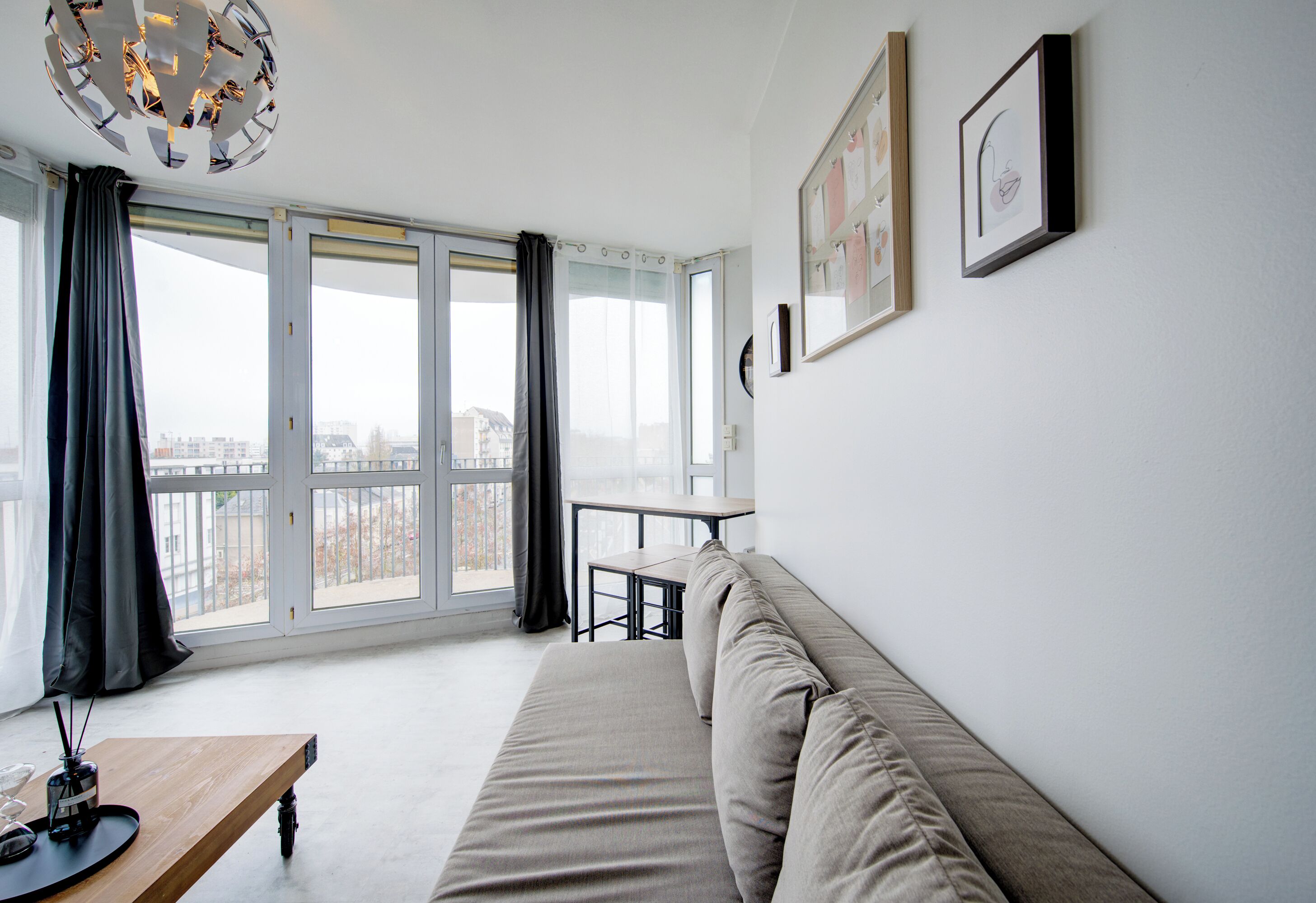 Una sala de estar moderna con un sofá, una mesita y vistas amplias a través de grandes ventanales.