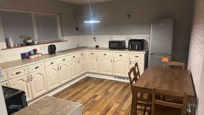 A compact kitchen with white cabinets, a wooden dining table, and a refrigerator. - Honeyhill Retreat in Peterborough (Peterborough)