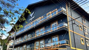 A multi-story hotel with a dark facade, balconies, and a sign with a bird logo.