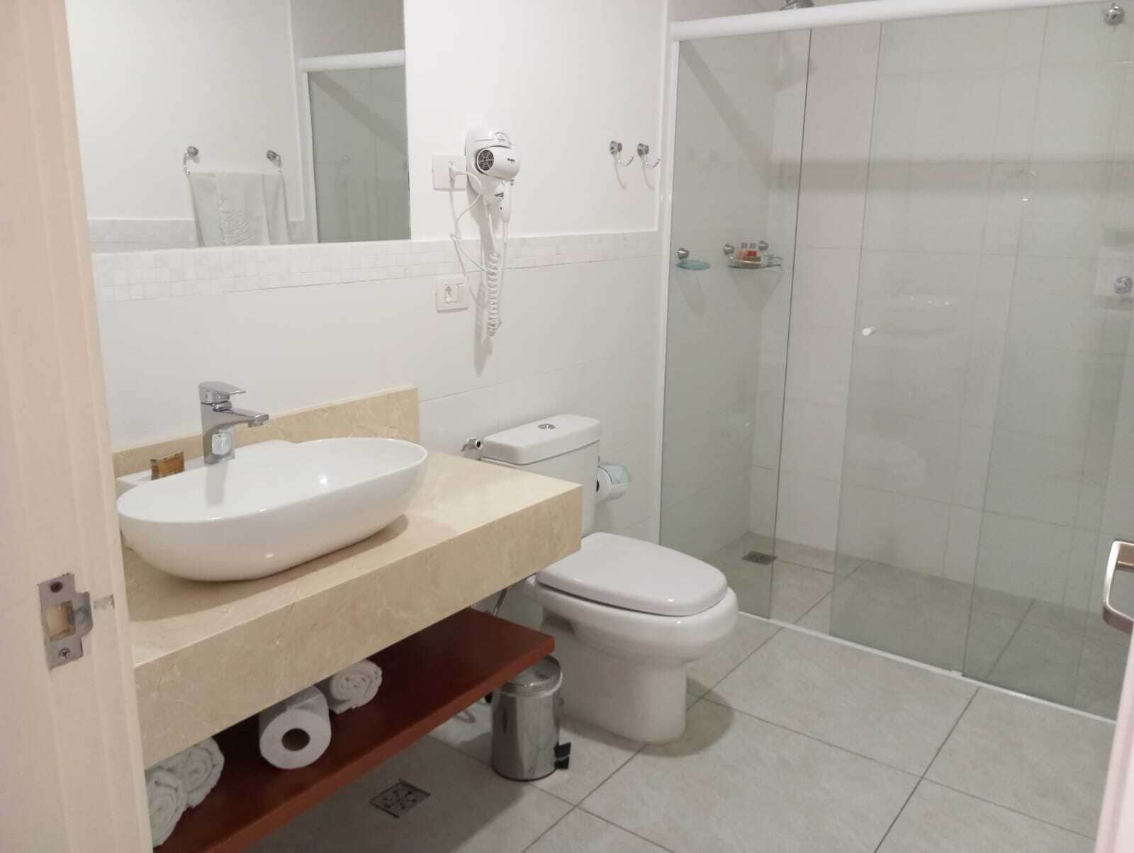 A bathroom with a white sink, toilet, and glass shower enclosure.