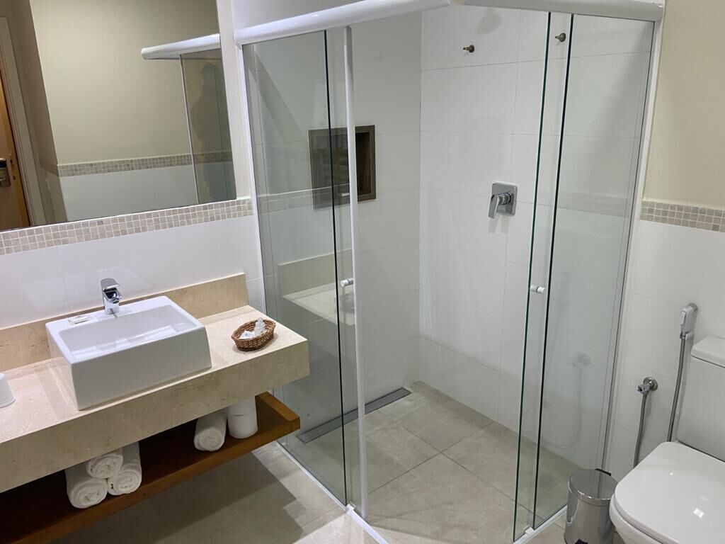 A modern bathroom with a glass-enclosed shower, a white sink, and a toilet.