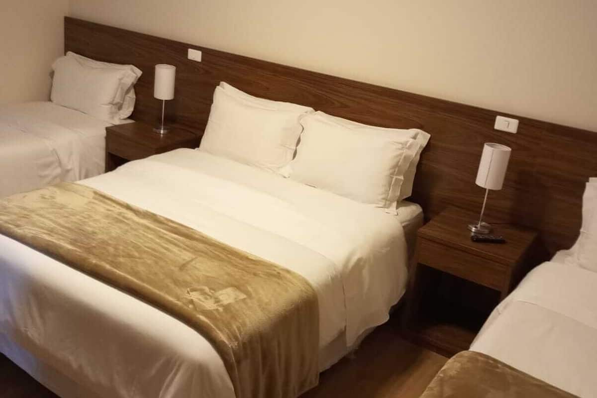Une chambre d’hôtel avec un grand lit, deux tables de chevet et une tête de lit en bois.