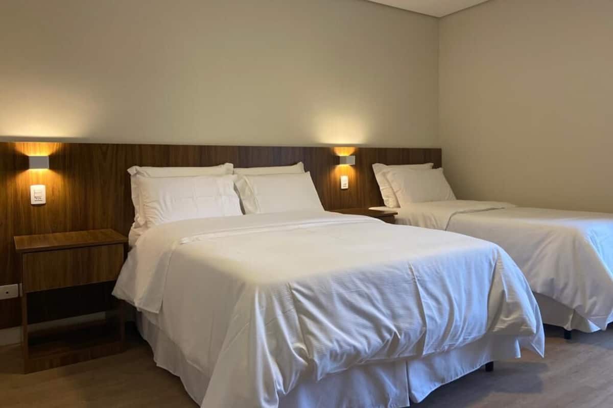 Une chambre d’hôtel avec deux lits, chacun doté d’une tête de lit en bois et de lampes de chevet.