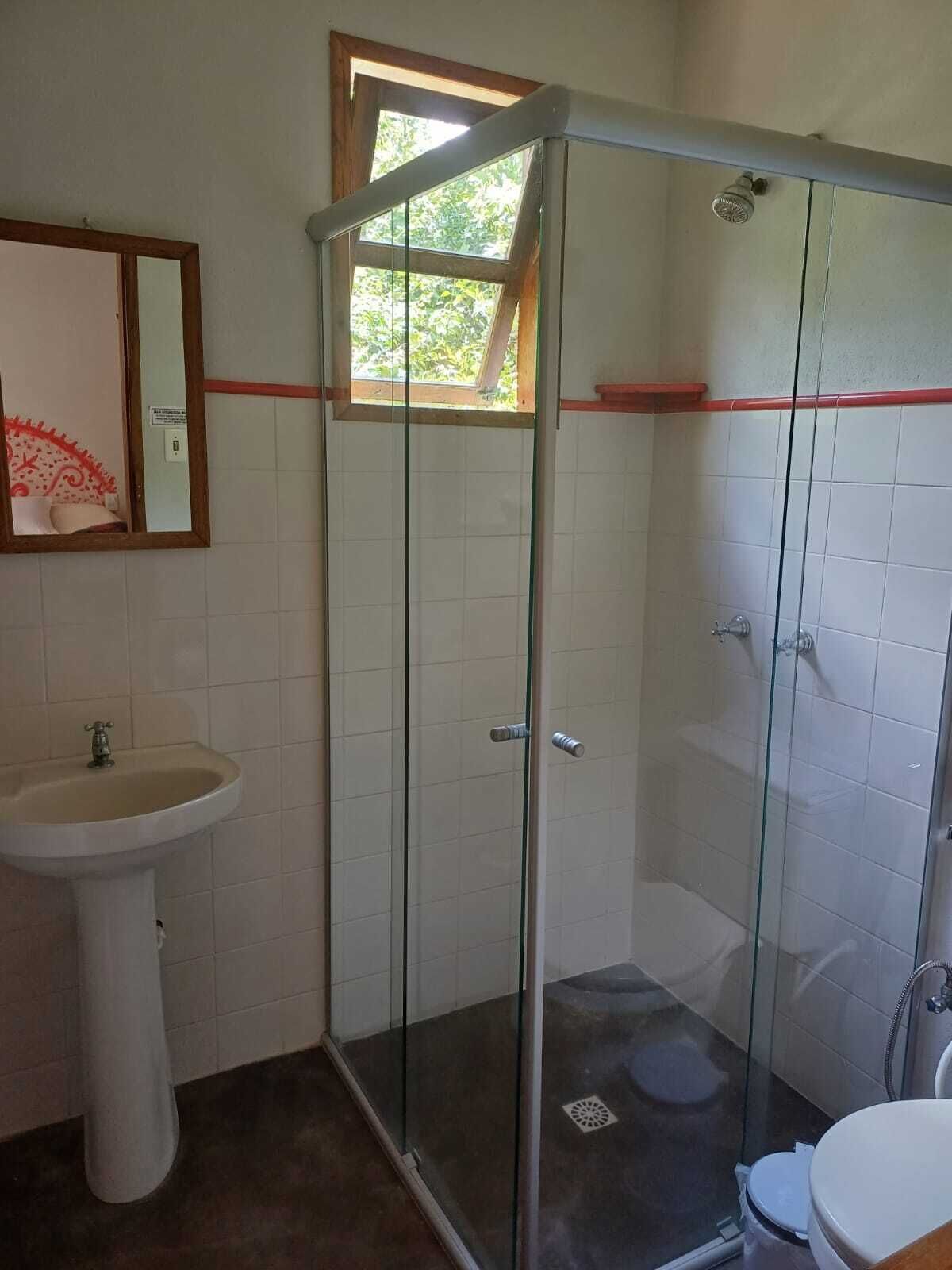 Een badkamer met een douchecabine, een wastafel op een zuil en een toilet.
