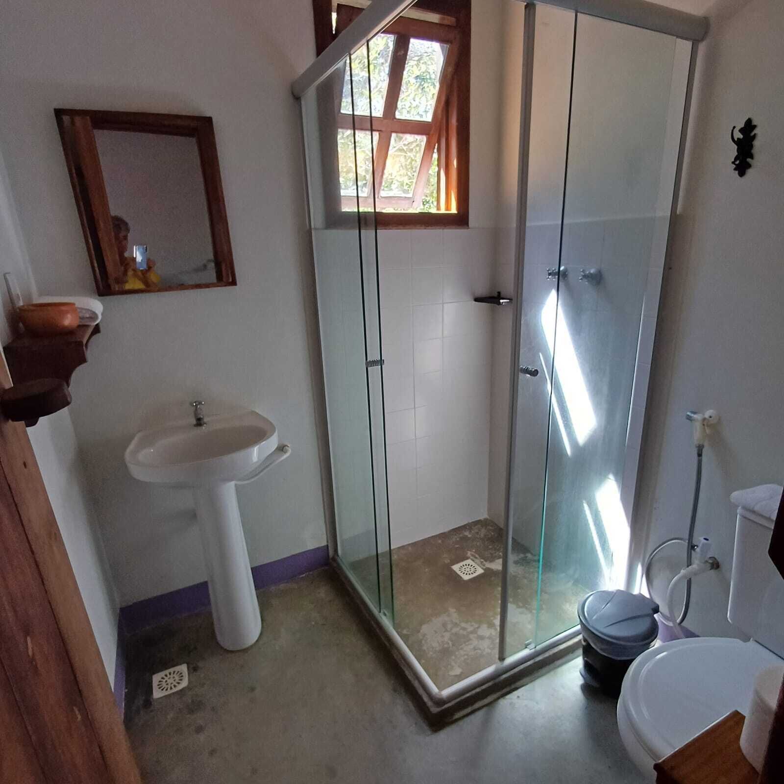 A bathroom with a glass-enclosed shower, a pedestal sink, and a toilet.