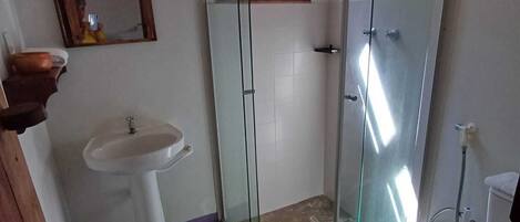 A bathroom with a glass-enclosed shower, a pedestal sink, and a toilet.