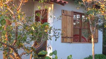 A house with a white exterior, a red-tiled roof, and a window with a wooden shutter.
