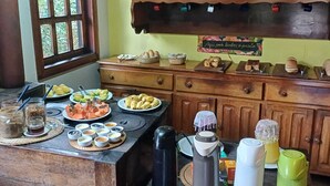 A kitchen with wooden cabinets, a window, and various food items and kitchenware on the counter. - Pousada do Pequi (Serro)