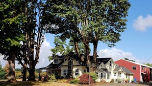 A large house with a red garage, surrounded by large trees and a clear sky. - Spacious 1930s, 5 bedroom farmhouse on 5 acres. AC/Heating and Wifi (Junction City)