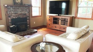 A living room with a fireplace, a television, and a sofa. - Spacious 1930s, 5 bedroom farmhouse on 5 acres. AC/Heating and Wifi (Junction City)