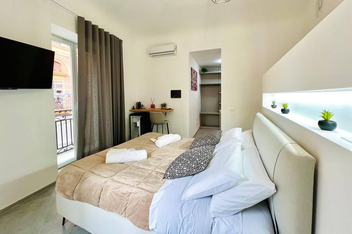 Et moderne hotelværelse med seng, skrivebord og balkon.