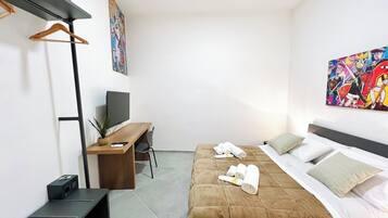 Una habitación de hotel moderna con cama, escritorio, televisión y obras de arte en las paredes.