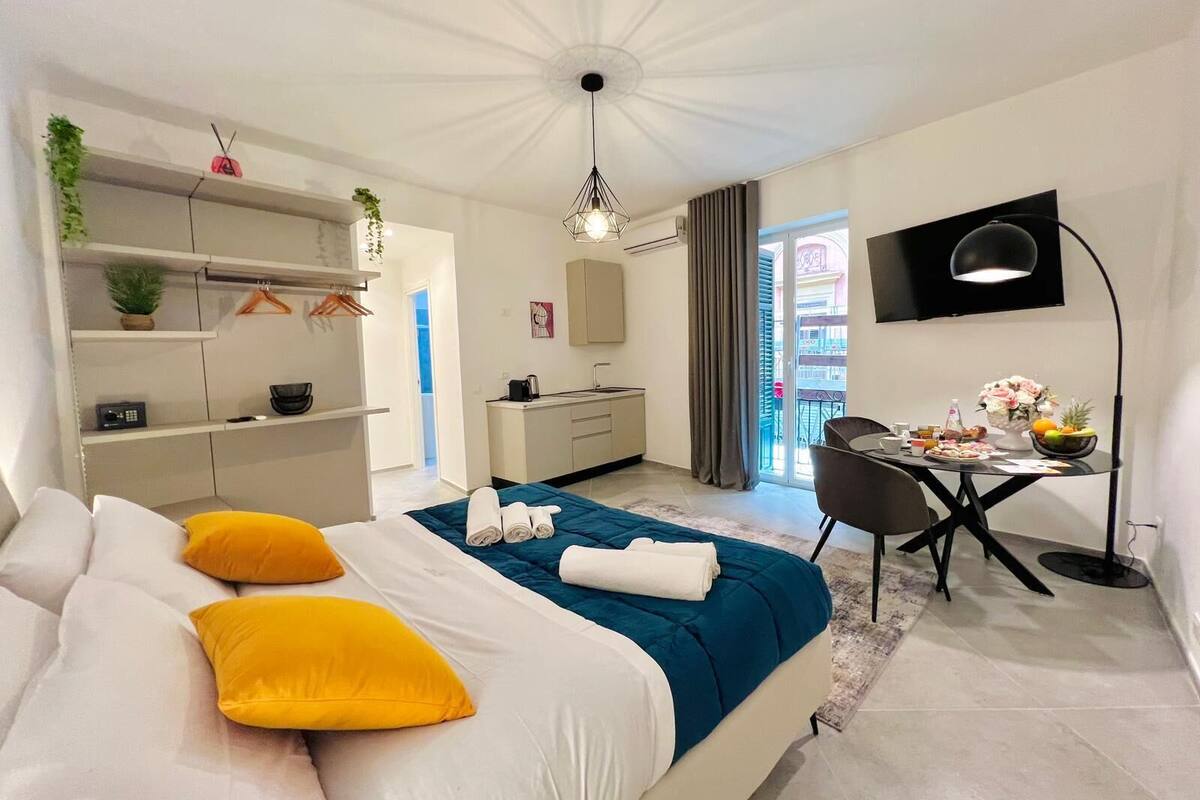 Et moderne soveværelse med seng, sengeborde, et skrivebord og udsigt til en balkon.