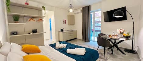 A modern bedroom with a bed, bedside tables, a desk, and a balcony view.