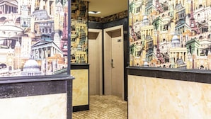 A hallway with a patterned wall depicting various buildings and a sign indicating an exit. - Dan Pelatenium (Madinah)