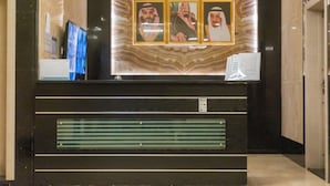 A reception desk with a marble backdrop, framed photographs, and a digital display. - Dan Pelatenium (Madinah)