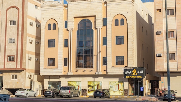 A hotel with a large central arched window, multiple smaller windows, and a sign for the Dan Platinum Hotel. - Dan Pelatenium (Madinah)