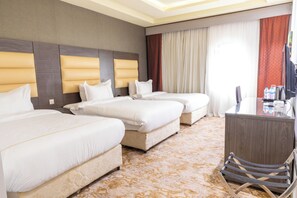 A hotel room with three beds, a desk, and a chair.