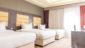 A hotel room with two beds, a desk, and a large window with curtains. - Dan Pelatenium (Madinah)