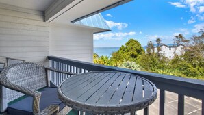A balcony with wicker furniture and a view of the ocean and buildings. - Cozy 1-bedroom condo in adorable Tybee Island (Tybee Island)