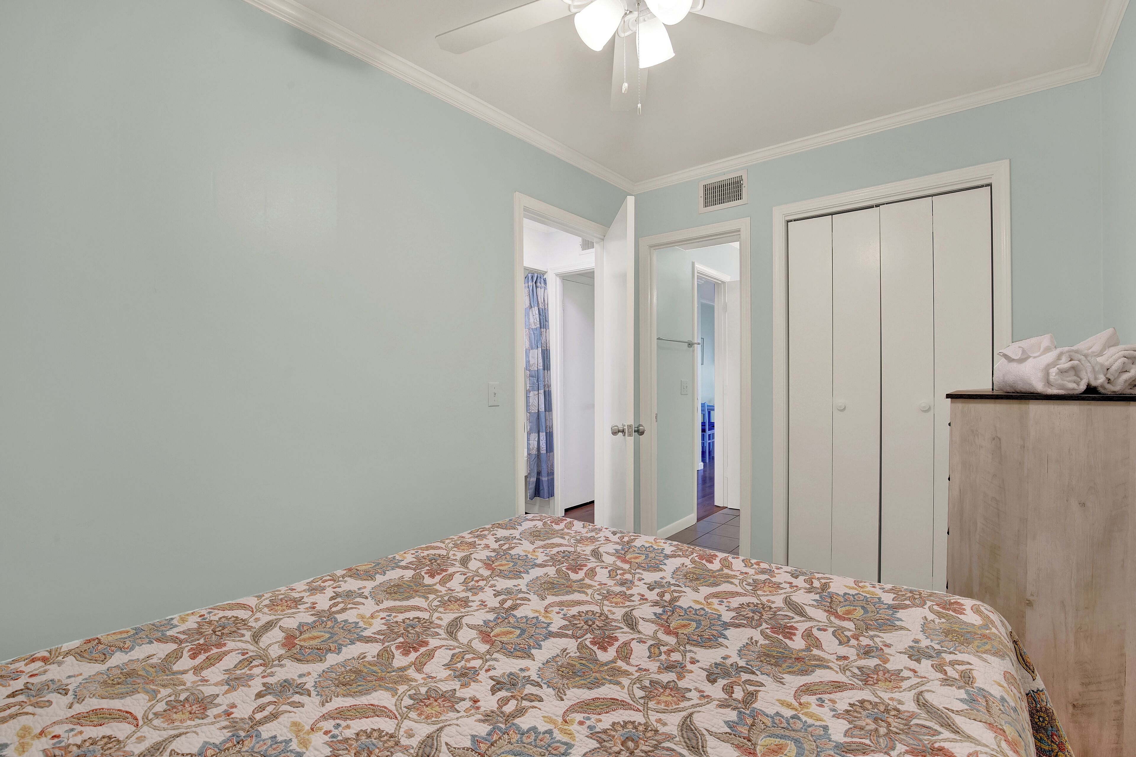 Un dormitorio con cama, armario y ventilador de techo.