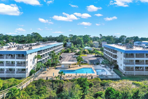 Un hotel con varios pisos, piscina y área de estacionamiento.