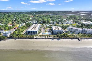 A high-rise hotel with multiple floors, a rooftop pool, and a view of a coastal area with a river.