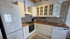 A kitchen with white cabinets, a built-in oven, a dishwasher, and a wooden countertop.
