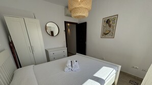 A hotel room with a bed, a wardrobe, a dresser, a mirror, and a painting on the wall.