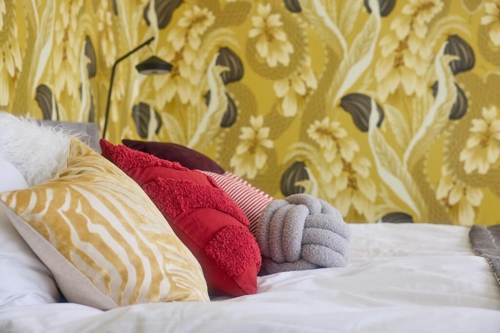 Una cama con varias almohadas y un fondo de papel tapiz estampado.
