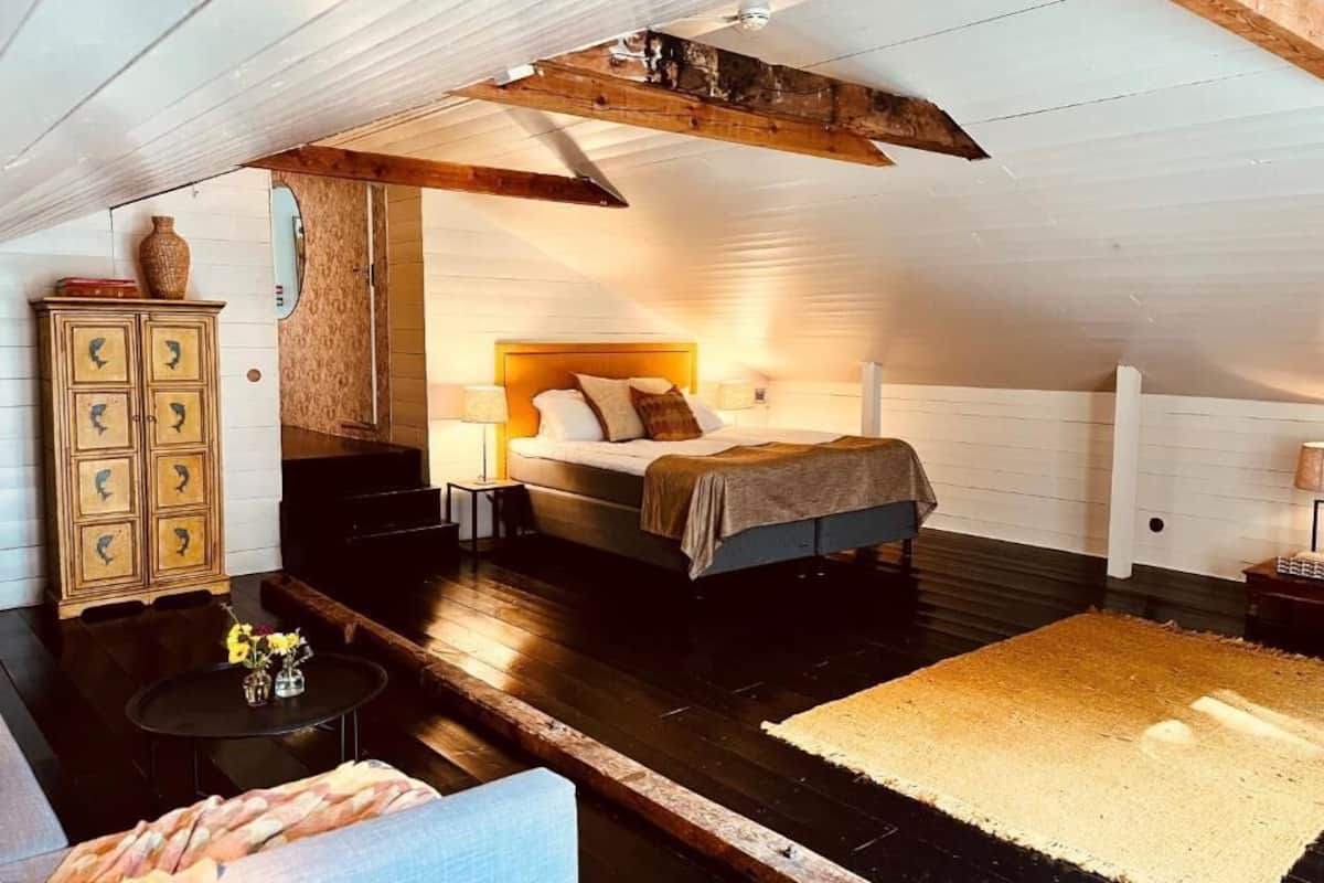 Ett sovrum med en säng, en byrå, ett sängbord, en lampa och en matta.