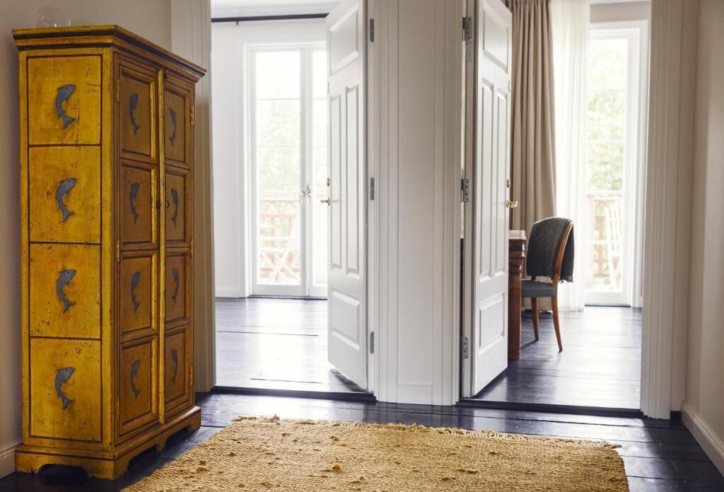 A room with a wooden cabinet, a door leading to an outdoor area, and a chair.