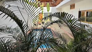 Un atrio de varios niveles con una piscina central rodeada de exuberante vegetación tropical.